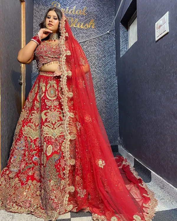 A classic red bridal lehenga with intricate gold embroidery, perfect for traditional wedding shoots. The double dupatta adds a royal touch.