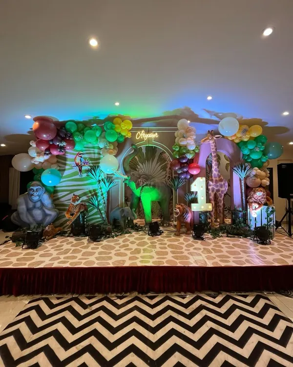 A spectacular 'Wild One' jungle safari stage. I used life-sized props of a gorilla, elephant, and giraffe, along with a custom printed floor and a lush balloon garland to create this immersive scene.