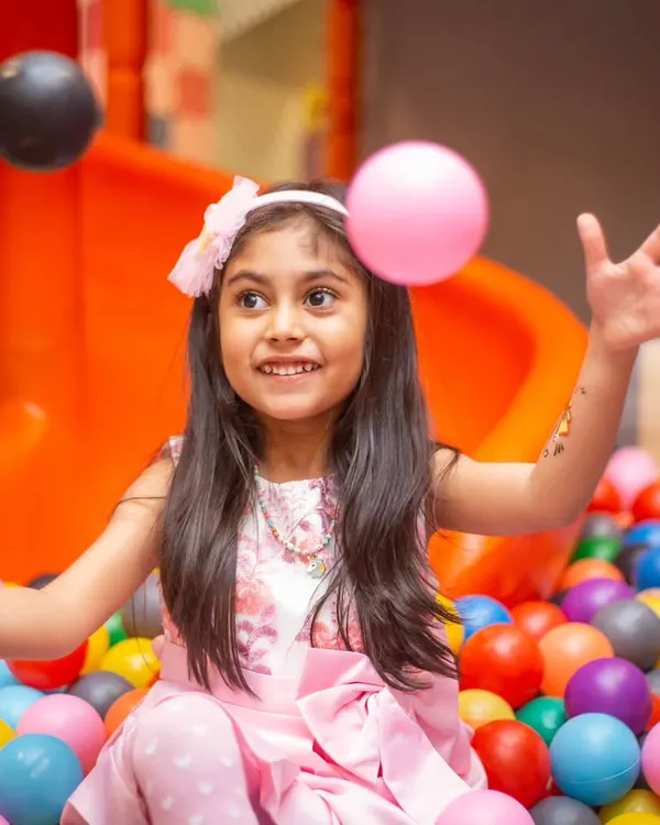 The pure joy of being surrounded by colorful balls in the ball pit. This action shot captures a moment of carefree happiness.