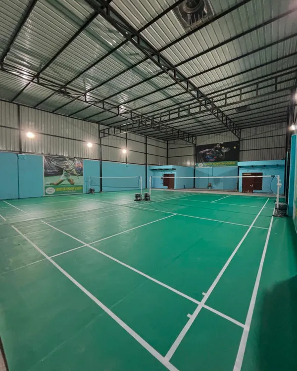 A clear, wide view of our new, professionally maintained indoor badminton court at the Sector 9B Gurugram center, featuring green synthetic mats and excellent overhead lighting.