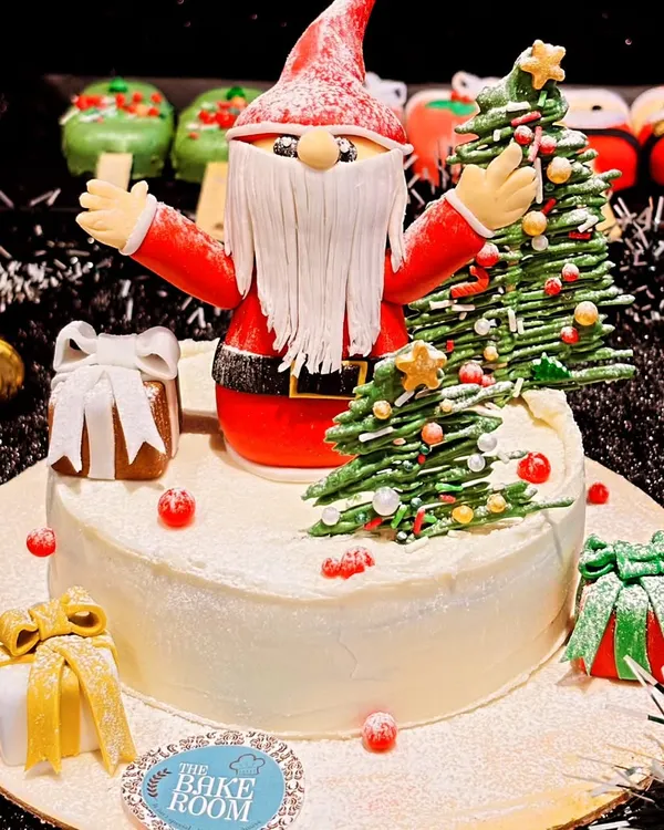 My centerpiece Christmas cake featuring a handcrafted Santa Claus and a Christmas tree. This cake is surrounded by festive details like gift boxes and is perfect for a large family gathering.