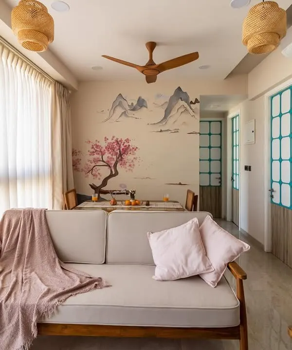 This Japandi-style living and dining area is the heart of a tranquil Mumbai home. We used a palette of soft, natural materials, a custom cherry blossom wall mural, and ample natural light to create a space that feels both expansive and deeply calming, perfect for family gatherings.
