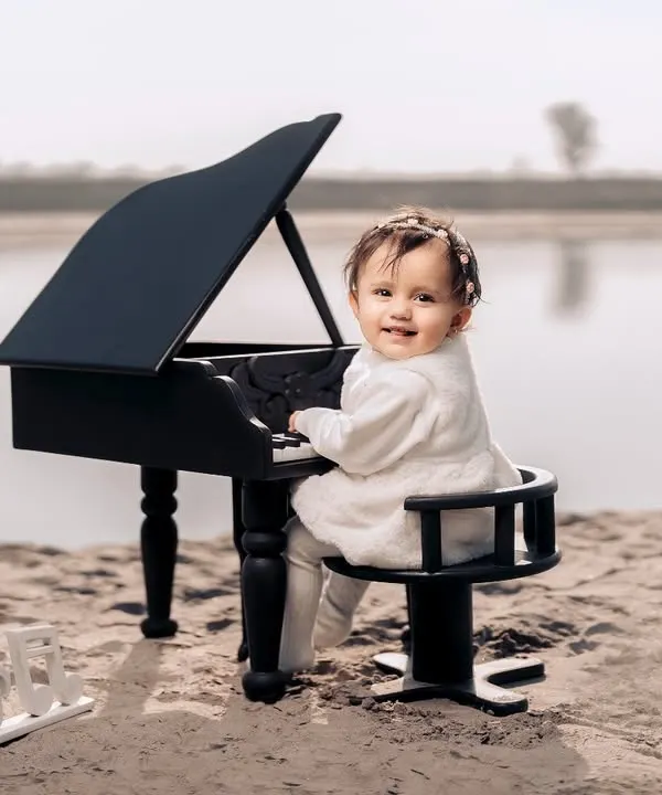 A tiny pianist creating her own melody by the water. This unique beachside setup with a miniature grand piano makes for truly magical and unforgettable photos.