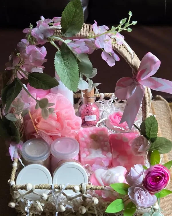 An elegant engagement hamper basket, beautifully decorated with pink flowers and filled with an assortment of my handmade pink-themed soaps, candles, and bath products.