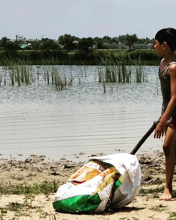 A child transports a heavy bag of freshly harvested clay from the lake bed. This is the first step in our earth-to-art process, connecting hard work with creative reward.