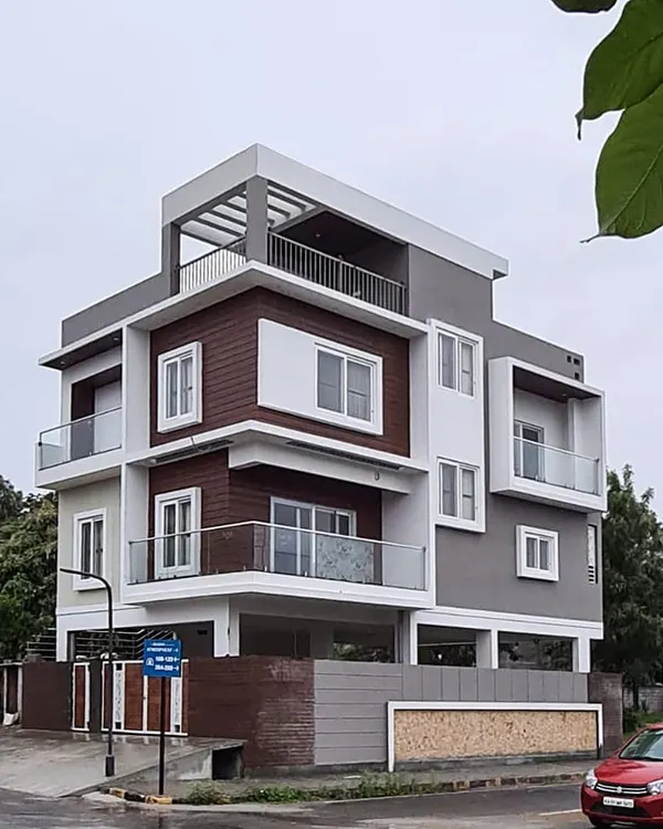 A completed residence at Bluejay Atmosphere, showcasing a clean, modern aesthetic. The design uses a balanced composition of white, grey, and wood-textured panels to define the elevation of this corner plot home.