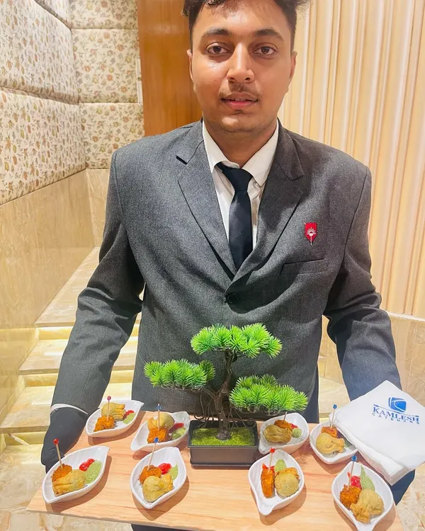 Our well-dressed staff presenting a tray of appetizers. The presentation, featuring a miniature bonsai tree, reflects our attention to detail and commitment to enhancing the overall dining experience.