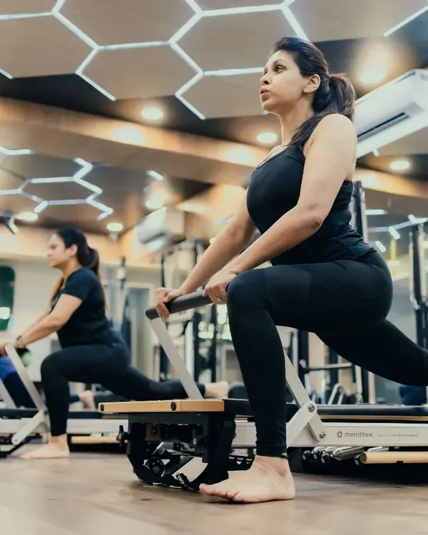 This is what a focused group session looks like. Each client works on achieving perfect posture and form during a reformer lunge, building strength and stability in a supportive environment.