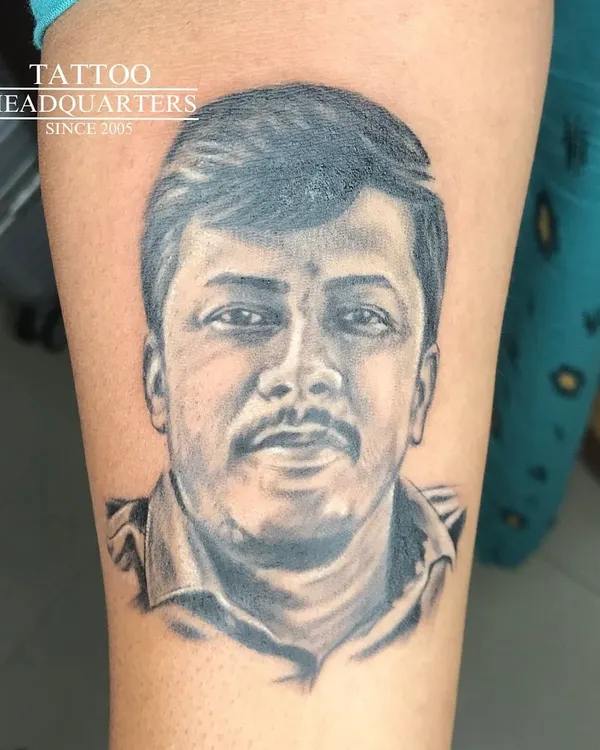 A realistic portrait tattoo capturing a gentle and warm expression. Our black and grey work focuses on soft shading to bring the image to life.