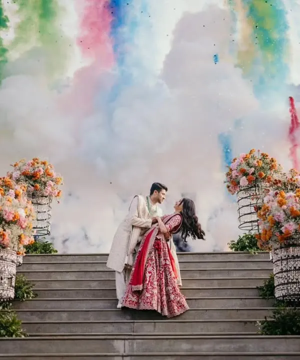 A picture perfect moment for the couple, framed by vibrant floral arrangements and a spectacular burst of rainbow-colored smoke. This is how I turn your engagement day into an unforgettable memory.