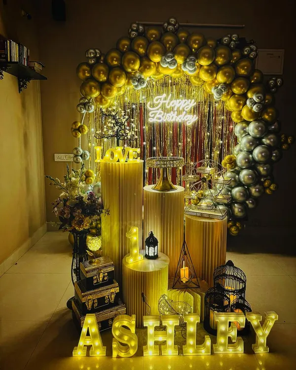 This is my signature elegant birthday setup, perfect for making anyone feel special. It features a full circular arch with gold and silver chrome balloons, a sparkling shimmer curtain with fairy lights, a custom neon sign, and illuminated marquee letters for the name. The look is completed with a full set of matching cylindrical stands and decorative props for the cake and dessert display.