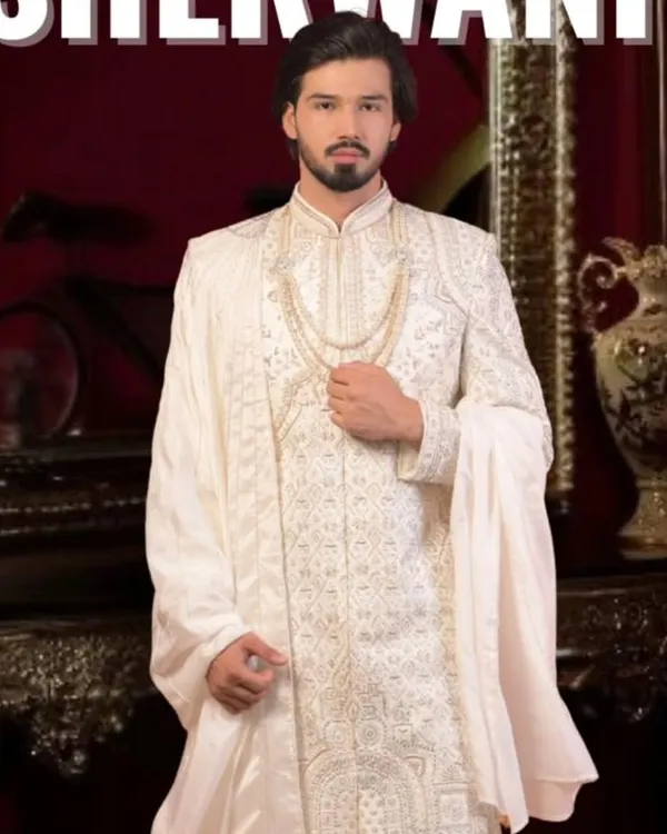 This is our classic ivory white sherwani, a timeless choice for any groom. We focus on intricate embroidery and a majestic fit, ensuring you look nothing less than royalty on your wedding day. We can customize the fabric and detailing just for you.