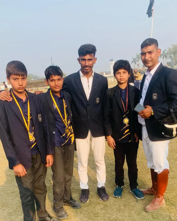 An instructor stands proudly with young riders, who are displaying the medals they earned through their hard work and success in competition.