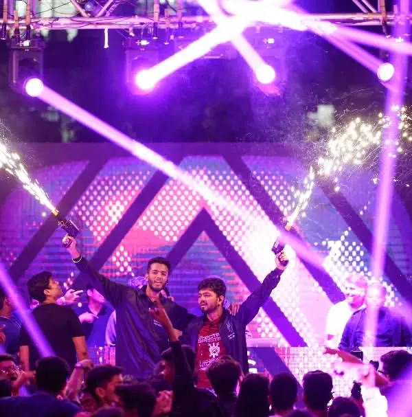 The main stage of a college fest comes alive with performers, pyrotechnics, and laser lights.