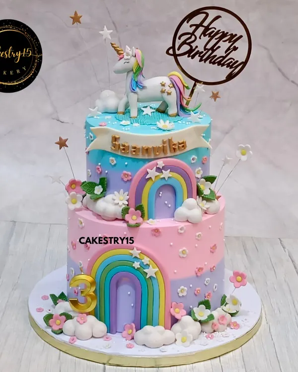 A magical two-tier unicorn cake in a beautiful pastel palette. This choco-vanilla cake is adorned with a handcrafted unicorn, fondant rainbows, fluffy clouds, and delicate flowers for a dreamy birthday celebration.