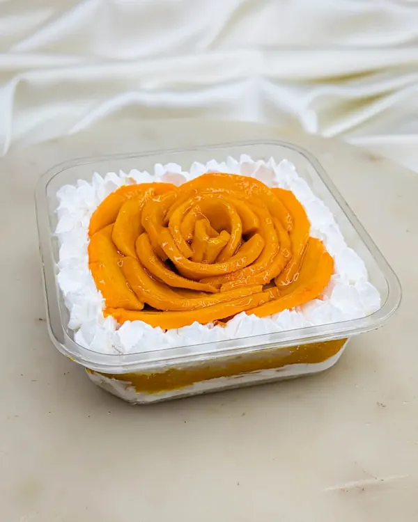 When mango season arrives, so does our Mango Fresh Cream Cake Tub. We use our signature moist vanilla sponge, layer it with homemade Aamras and fresh diced mangoes, and top it with a beautiful mango rose. It's a light, refreshing summer dessert.