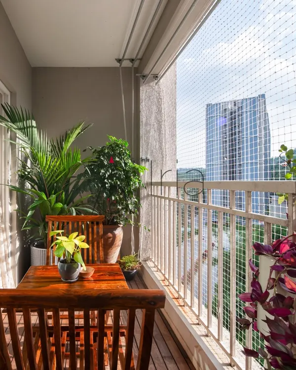 This balcony view shows how even with a safety net, a green and pleasant space can be created. The plants are positioned to thrive while offering a beautiful view of the city beyond.