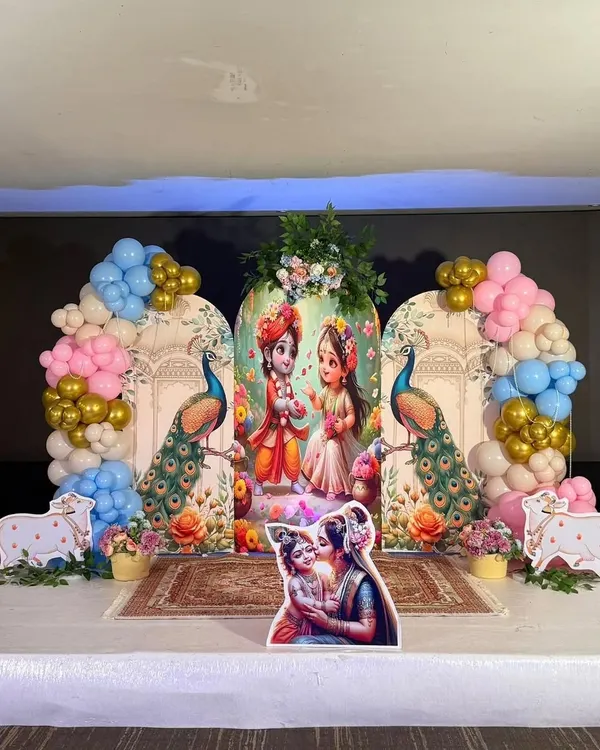 Celebrating Janmashtami with a divine touch. We created this beautiful stage setup featuring Radha and Krishna, decorated with peacock elements and colorful balloon arches in pastel and gold.