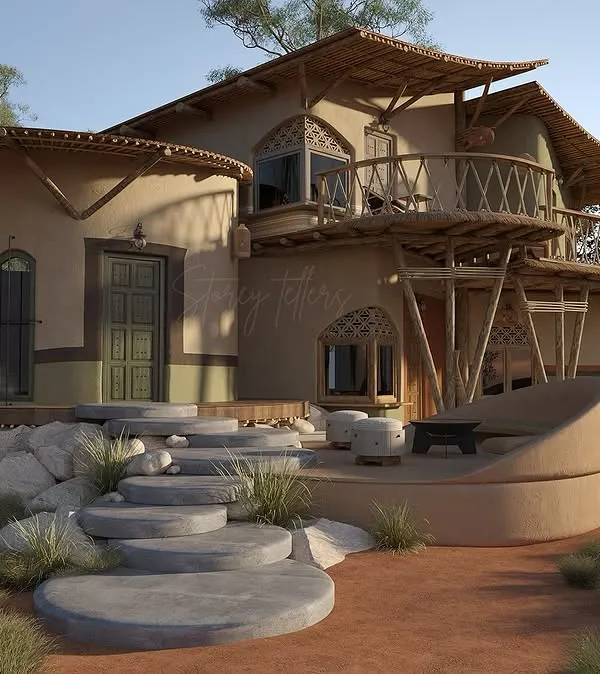 The guest units at Driftwood are designed to feel like private sanctuaries nestled in nature. This view shows the organic forms of the building, with its curved walls and thatched roofing, rising from the landscape. The stone steps and earthen patio blur the boundary between inside and out.