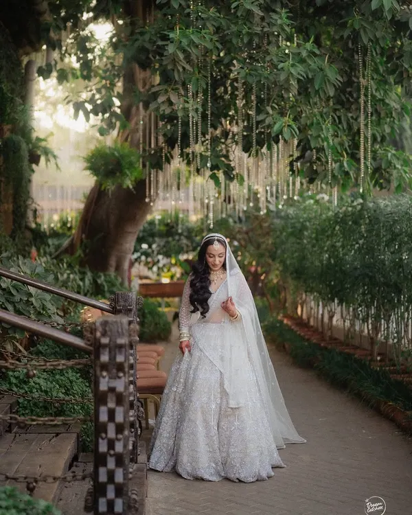 A beautiful shot of the bride walking along a garden path, her veil trailing behind her, creating a sense of movement and grace.