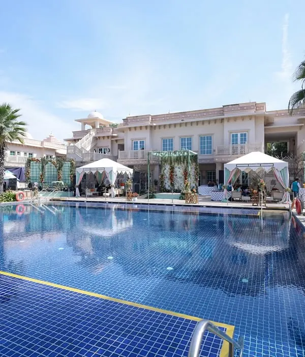 A wide shot of a "Tropical Oasis" themed poolside event, featuring canopies, lounge seating, and a fresh, vibrant color palette.