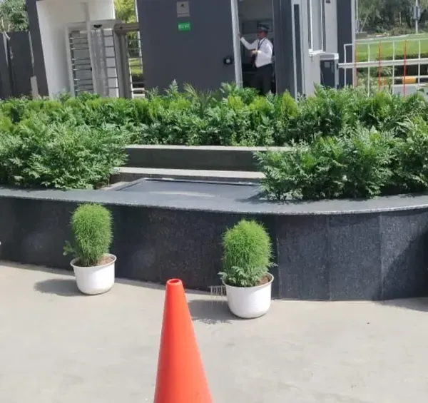 A formal and structured entrance design for a corporate facility. The combination of a manicured hedge within a stone planter and uniform potted shrubs creates a clean, professional, and welcoming first impression.