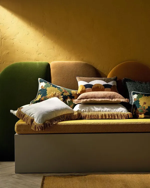 A plush arrangement of cushions from the Fall Winter 2024 Accessories Collection. This assortment showcases a rich blend of textures, from fringed linens to patterned jacquards and abstract velvets, demonstrating our artful approach to creating layered, comfortable, and visually stimulating accents.