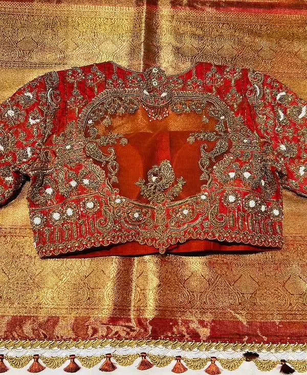This bridal blouse, crafted in rich red raw silk, is fit for royalty. The design features exquisite hand embroidery with pearl and zardozi work around a sheer organza panel, creating a look of pure opulence.