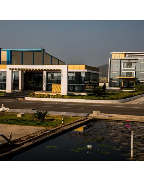 A view of the Krishna Sai Granites campus, showcasing the relationship between the main processing facility and the contemporary admin block. We integrated landscape elements like a water feature to soften the industrial context and create a more pleasant working environment.