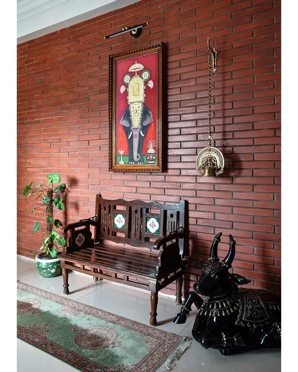 The private foyer welcomes you with a gorgeous brick-clad wall and a traditional Tanjore painting of a tusker elephant. This space immediately introduces the home's theme of warmth, art, and cultural heritage.