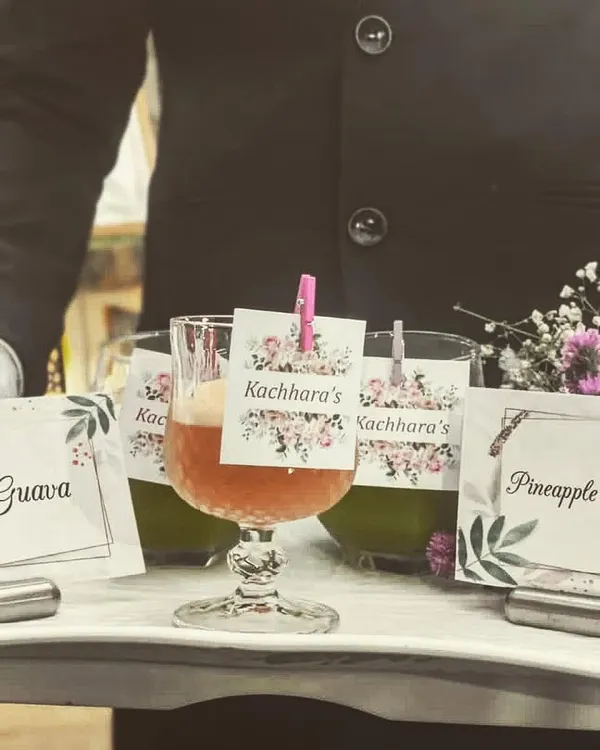 Impeccable service extends to our beverage offerings. Here, a member of my team presents freshly made juices, including Orange Guava and Pineapple Kiwi Mint, with personalized labels for the event.