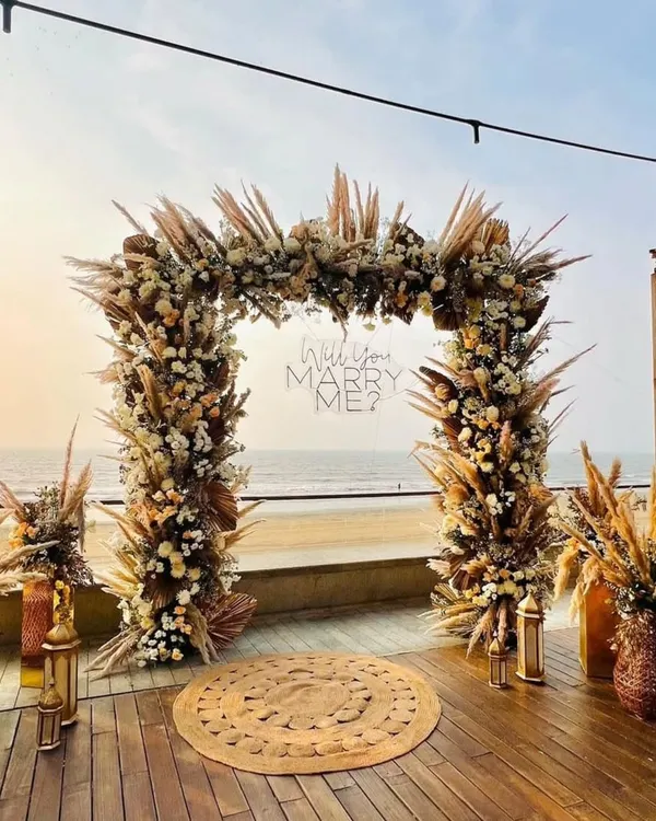 This is the full view of a boho-themed proposal I set up at Grey Goose, right by the sea. The floral arch, pampas grass, and jute rugs create a perfect romantic pathway for the big question.