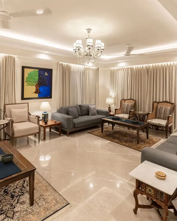 We believe a living room should be a sanctuary of comfort and elegance. In this space, we combined plush grey sofas with classic wooden armchairs and tables to create a balanced and inviting atmosphere. The polished marble flooring reflects the layered lighting from the crystal chandelier and recessed ceiling lights, enhancing the sense of luxury and spaciousness.