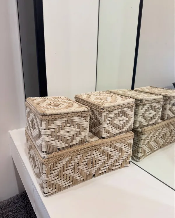 Our set of three woven storage boxes, shown here on a dresser. They are perfect for organizing jewelry, makeup, or other small essentials in a stylish way.