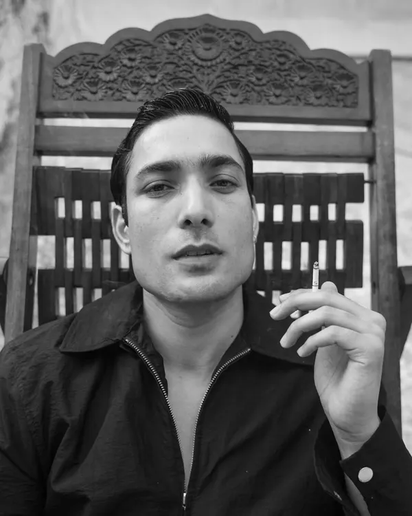 A classic, cinematic black and white portrait for a male actor. The direct gaze and the prop create a strong sense of character and story.