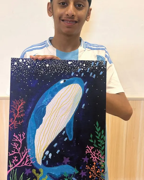 The proud moment when a masterpiece is complete! This student did an amazing job creating his own vibrant whale painting, learning about color blending and composition along the way.