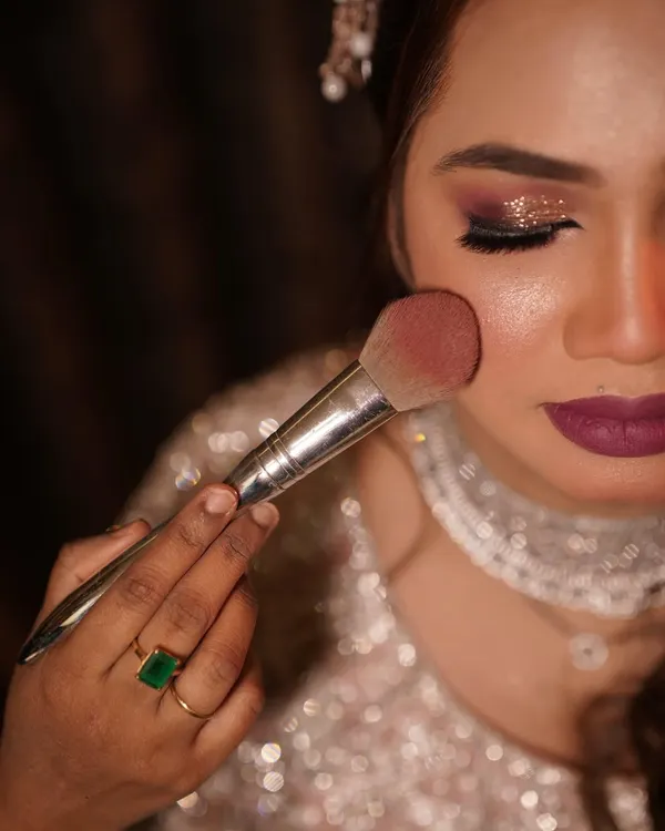 The final dusting of blush to add a healthy, rosy glow. This close-up shows the flawless texture of the skin and the beautiful shimmer on the eyes.