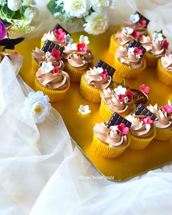 A set of my popular choco-vanilla cupcakes. I've topped the chocolate frosting with a small piece of dark chocolate and tiny, delicate sugar flowers for an elegant look.
