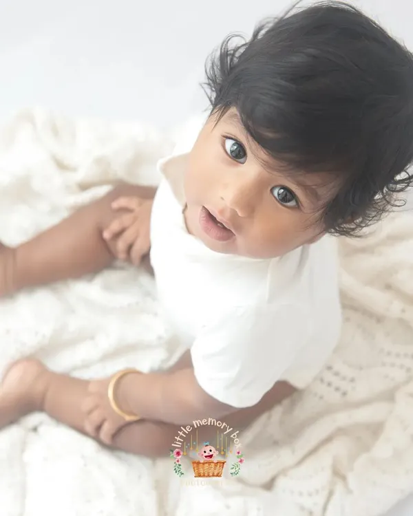 This is the essence of my minimalist style. A beautiful baby on a simple, soft white blanket. The focus is entirely on their innocent expression and bright eyes.