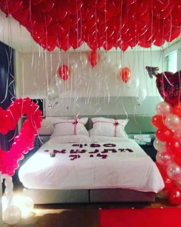 This is the ultimate romantic room decoration, with a ceiling completely covered in red balloons. I also added a large heart-shaped balloon sculpture and used rose petals to write a message on the bed for a grand romantic gesture.