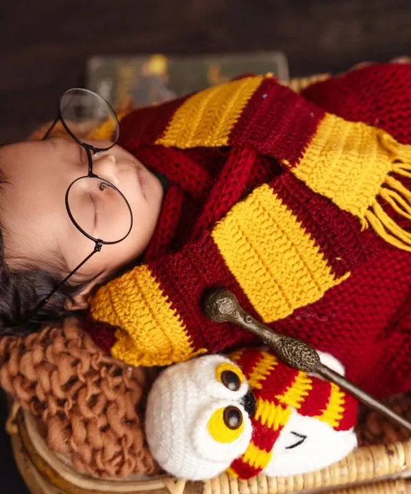 Welcome to Hogwarts. A sleeping newborn transformed into a tiny Harry Potter, safely swaddled in a Gryffindor-colored wrap and complete with iconic glasses and a magic wand.