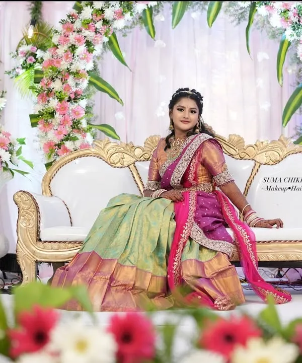 A doll-like look for a traditional half-saree ceremony. The vibrant colors of the outfit are matched with fresh, youthful makeup, making it a memorable day for the young lady.