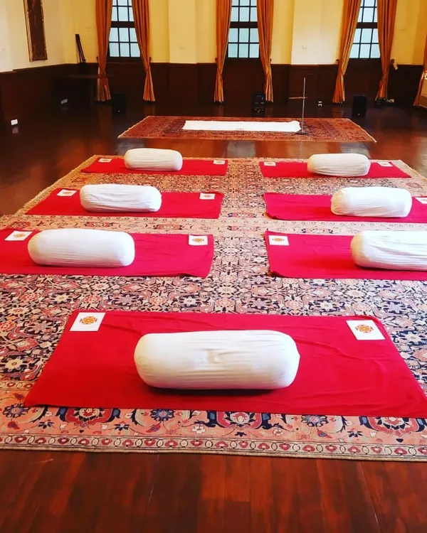 A yoga space prepared for a session, with mats and bolsters ready. The beauty of yoga is that it is for everyone, regardless of age or fitness level. It is a practice that calms the mind and strengthens the body.