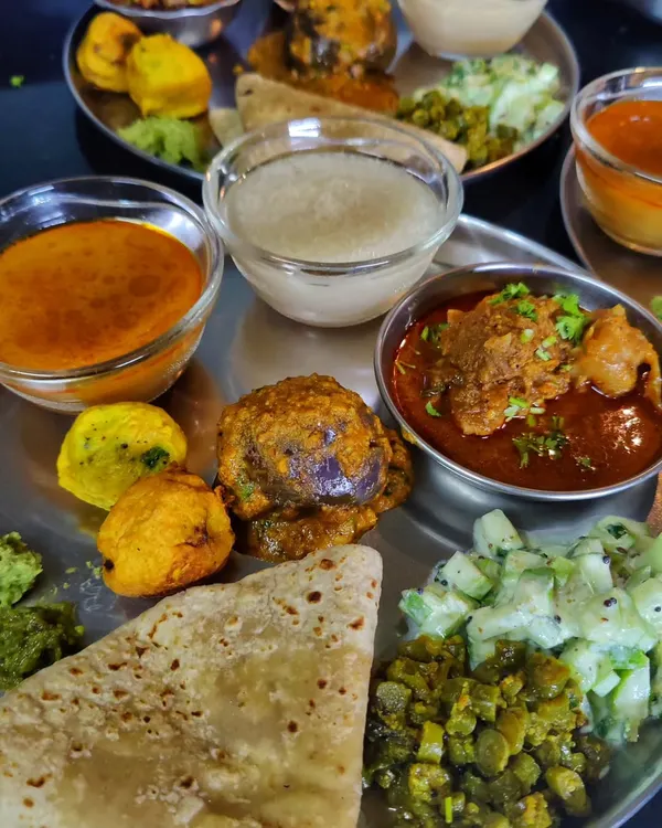 A close-up of my authentic Kolhapuri Thali. It features Bharlela Vanga (stuffed eggplant), spicy chicken curry, Pandra Rassa (white broth), and fresh koshimbir. This is the real taste of Kolhapur, far beyond just the spicy red curry.