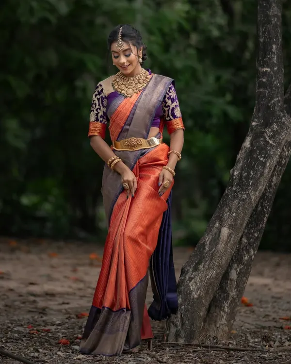 For the bride who wants tradition with a touch of glam, this bright orange and purple Kancheevaram silk beauty is made to dazzle.
