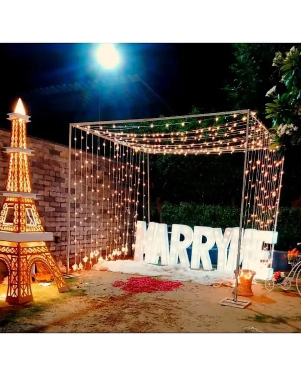 The ultimate proposal setup featuring large light-up "MARRY ME" letters under a canopy of fairy lights, creating a moment straight out of a movie.