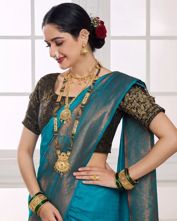 A model adorned in a full traditional Maharashtrian jewellery set, including a long haar and nath. The shot is framed to highlight the detailed craftsmanship against a vibrant blue silk saree, perfect for a bridal catalogue.