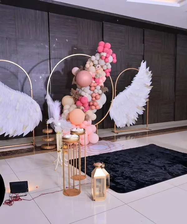 A breathtaking 'Angel Wings' theme we created for a baptism. This setup features large, feathered wings, a circular gold arch with a pastel balloon garland, and elegant pedestals, creating a heavenly photo opportunity for the special day.