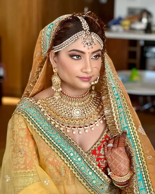 A regal bridal portrait featuring a classic Sabyasachi lehenga. The makeup was designed to be timeless, with bold eyes and glowing skin to complement the intricate gold jewelry and rich mustard tones of the outfit.