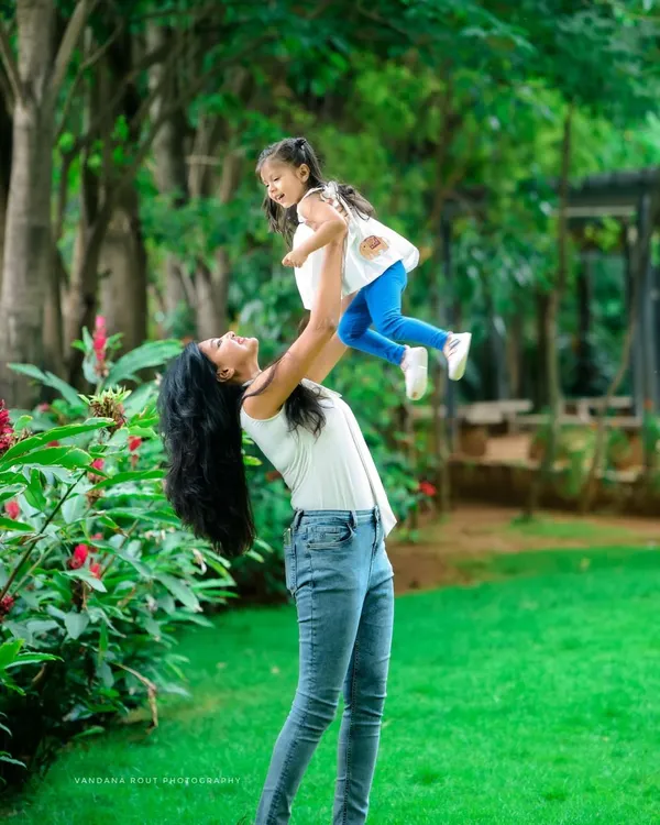 A mother joyfully lifts her daughter into the air in a beautiful park setting. I love capturing these dynamic, action-filled moments that show the pure fun of childhood.